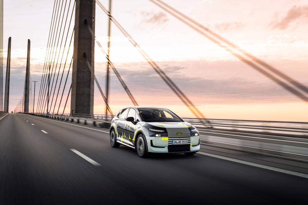 Audi A2 e-tron, prototyp w kamuflażu — tył i bok, jazda autostradą o zachodzie słońca