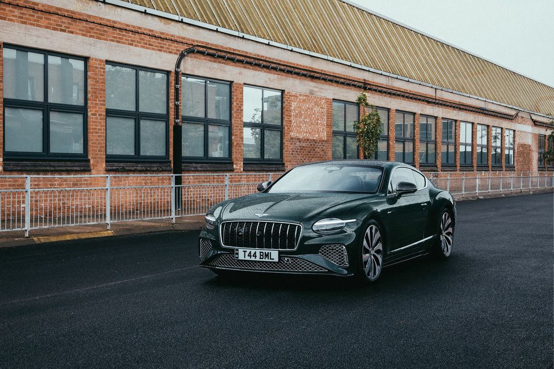 Bentley Continental GT Azure - przód, ujęcie 3/4 przy ceglanym budynku fabryki w Crewe