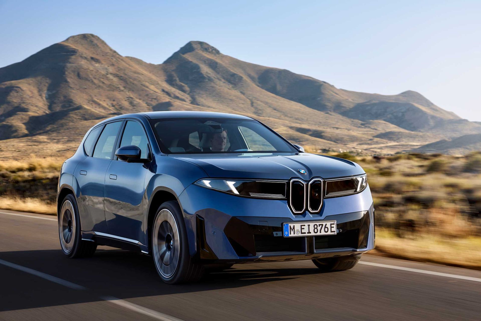 BMW iX3 40 — przód w jeździe dynamicznej, górski krajobraz w tle