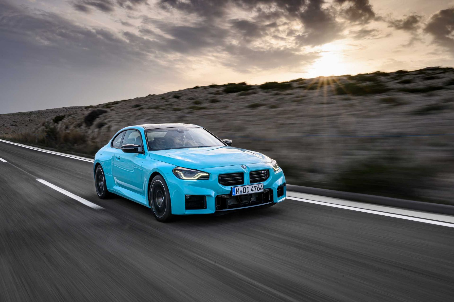 BMW M2 — przód/bok, jazda dynamiczna o zachodzie słońca, niebieski lakier