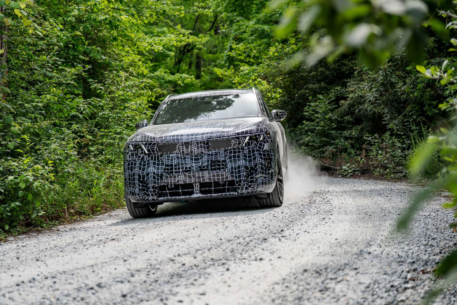 BMW X5 G65 — przód, prototyp w kamuflażu testowym podczas jazdy na szutrowej drodze leśnej