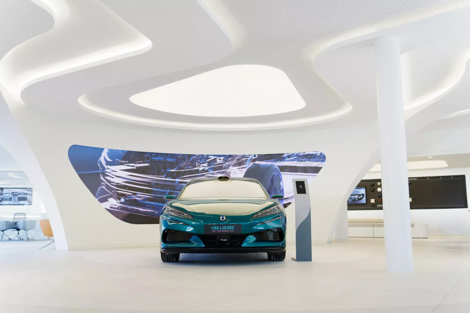 BYD — przód frontalny, turkusowa limuzyna w futurystycznym salonie z ekranami w tle