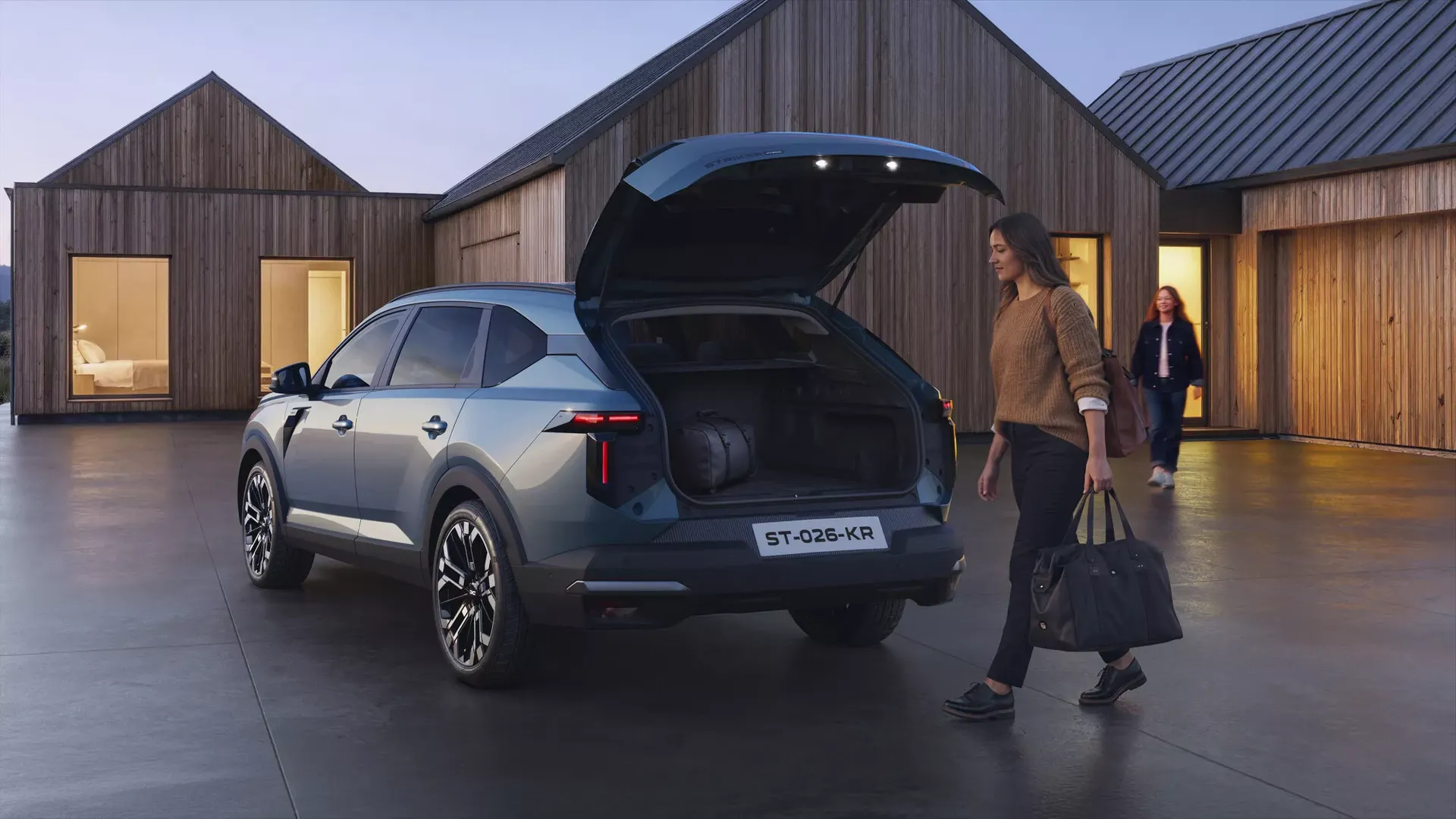 Dacia Striker — tył, kobieta pakująca torbę do otwartego bagażnika