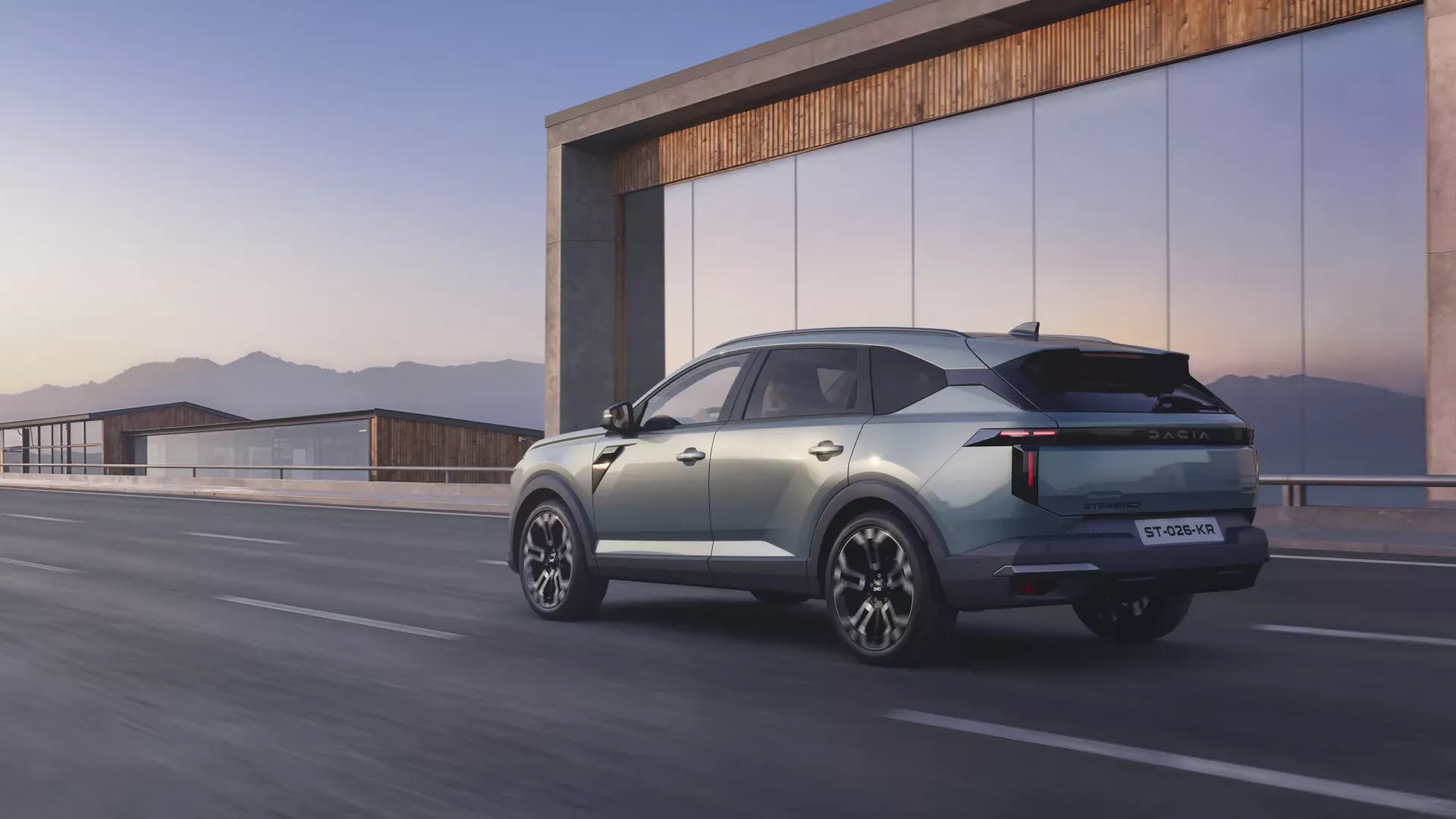 Dacia Striker — tył, jazda przy nowoczesnym szklanym budynku (ujęcie powtórzone z p04)