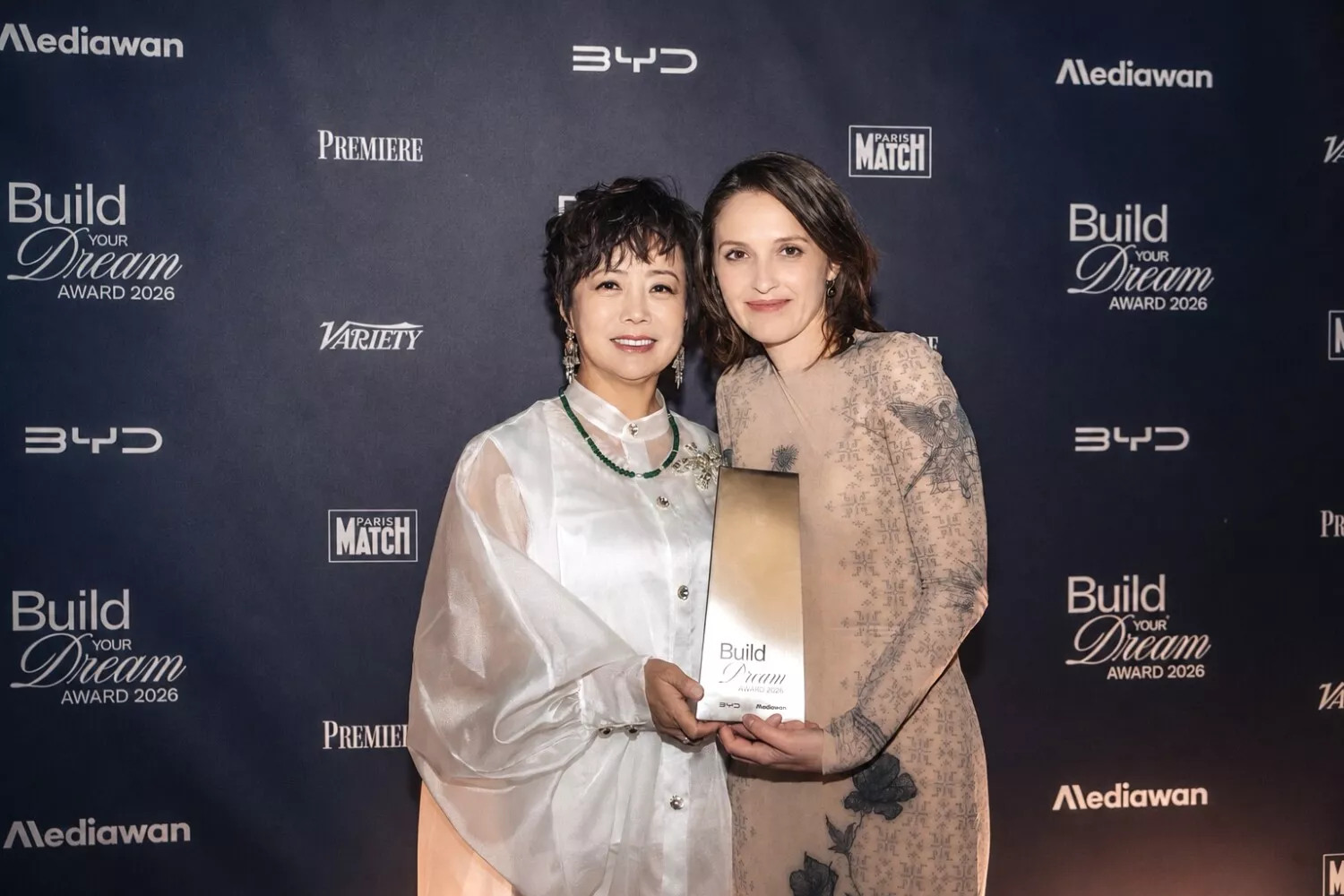 Ceremonia „Build Your Dream Award 2026” — dwie kobiety z nagrodą na tle bannerów BYD i Mediawan, brak samochodu