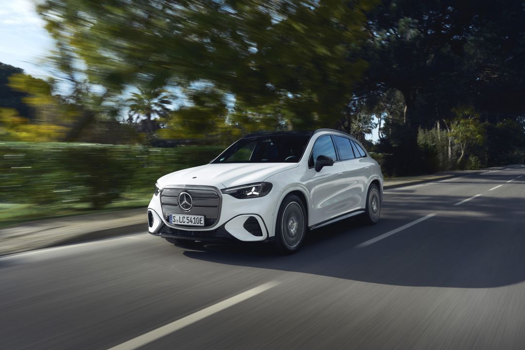 Mercedes-Benz GLC (elektryczny) — przód/bok, dynamiczna jazda drogą wśród drzew
