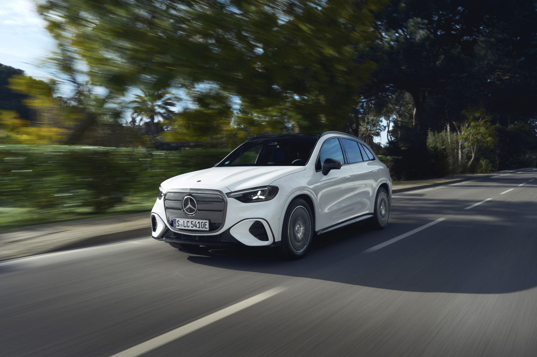 Mercedes-Benz GLC elektryczny — przód i bok 3/4, jazda na drodze między drzewami