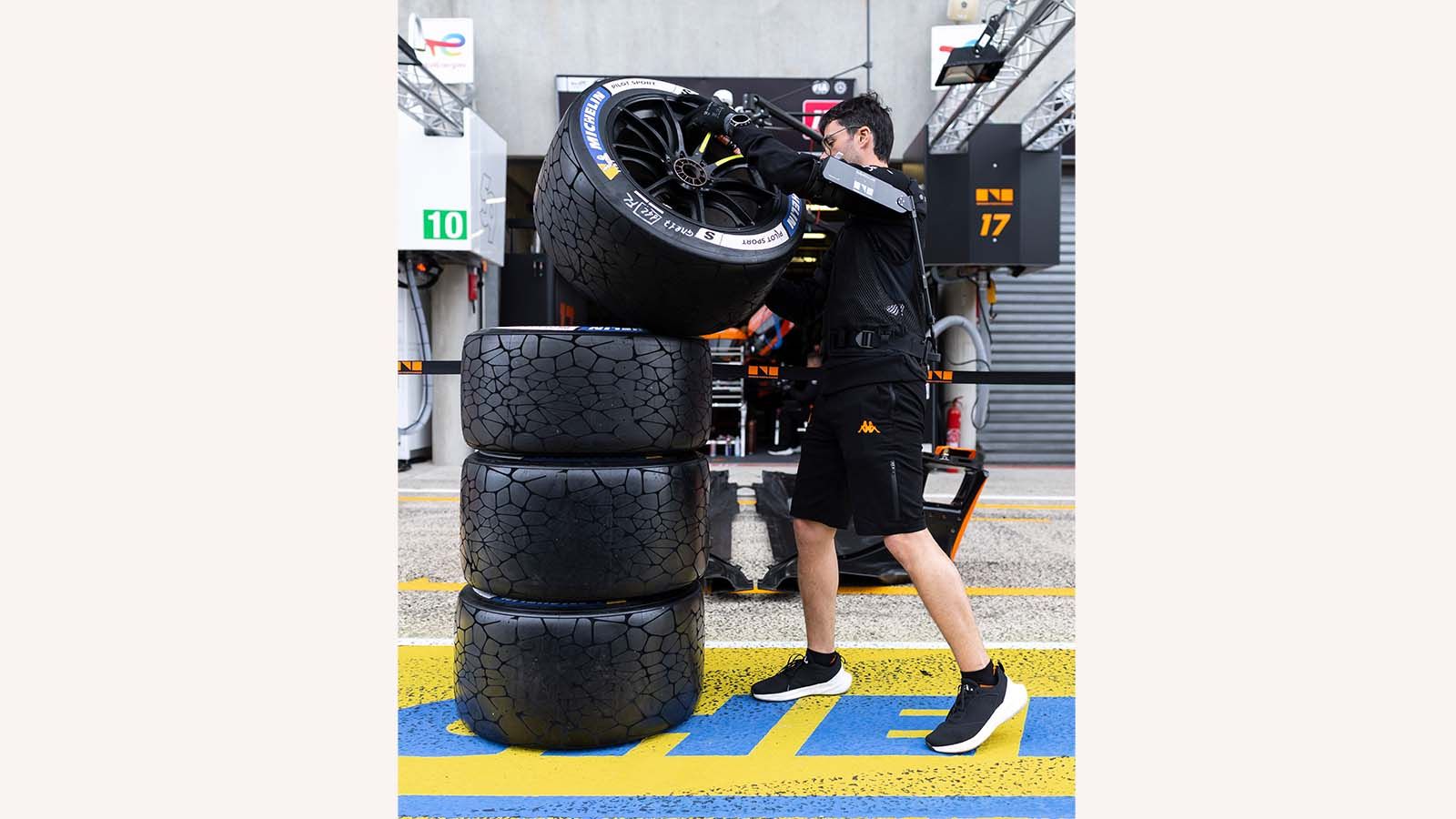 Kulisy Le Mans — mechanik Genesis Magma Racing układa stos opon Michelin w garażu