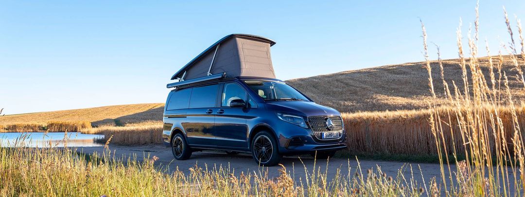Mercedes-Benz Marco Polo — panoramiczne ujęcie z boku, kamper z rozłożonym dachem na polnej drodze