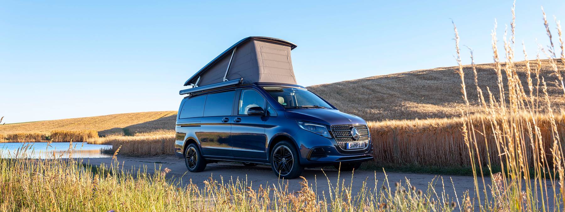 Mercedes-Benz Marco Polo — panoramiczne ujęcie z boku, kamper z rozłożonym dachem na polnej drodze