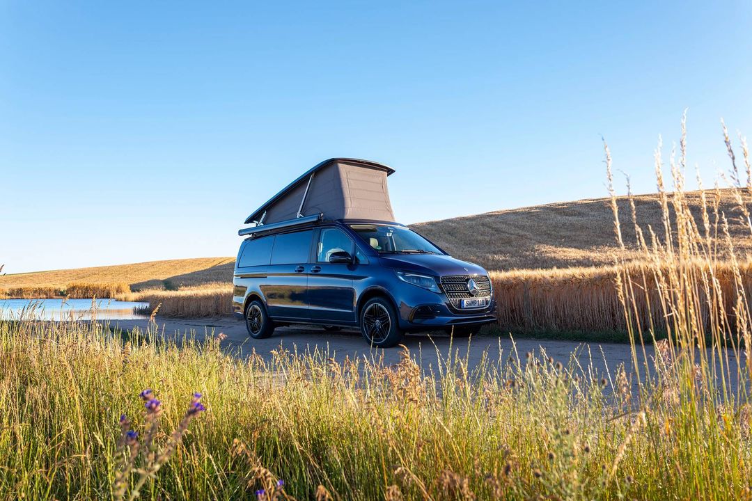 Mercedes-Benz Marco Polo — widok 3/4 przód, kamper z uniesionym dachem sypialnym przy trzcinach