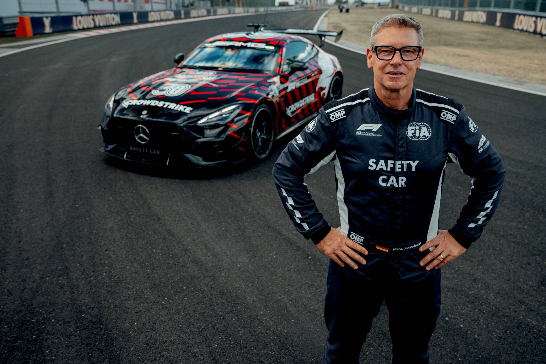 Kierowca safety car Bernd Mayländer w kombinezonie FIA, w tle zaparkowany Mercedes-AMG GT 63 PRO na torze