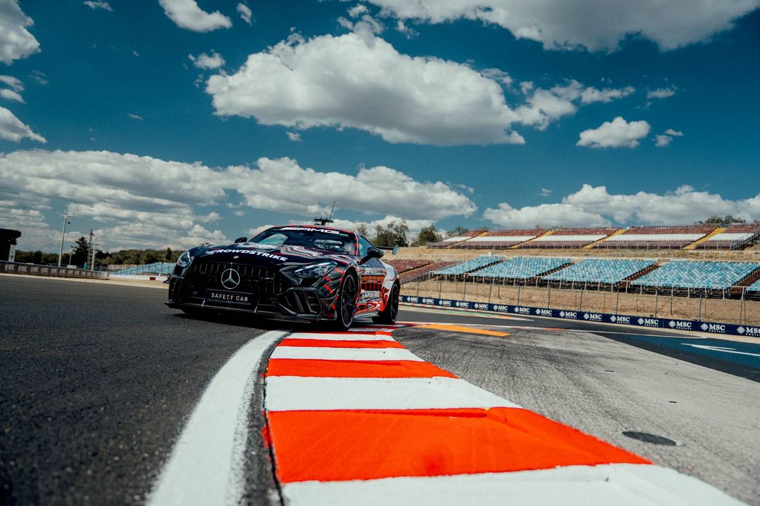 Mercedes-AMG GT 63 PRO – przód safety car w kamuflażu na pustym torze, dramatyczne niebo z chmurami