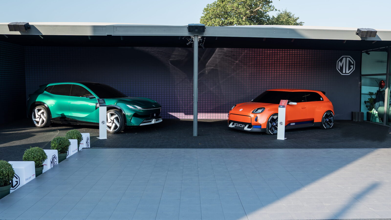 MG — dwa samochody koncepcyjne, zielony SUV i pomarańczowy hatchback, prezentacja pod zadaszeniem