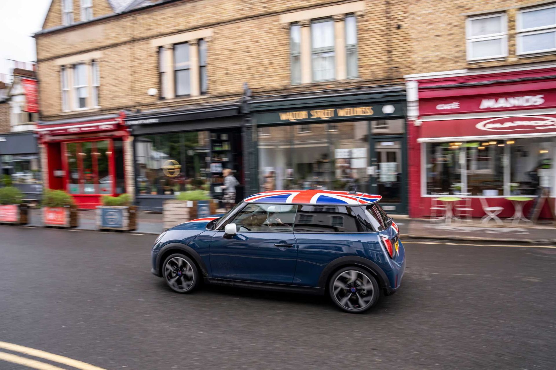 MINI Cooper Oxford Edition — bok, dynamiczna jazda brytyjską ulicą handlową, dach w barwach Union Jack