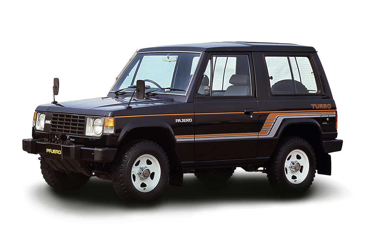Mitsubishi Pajero I generacja (1982) — przód 3/4, kolor czarny z pomarańczowymi pasami, tło studyjne
