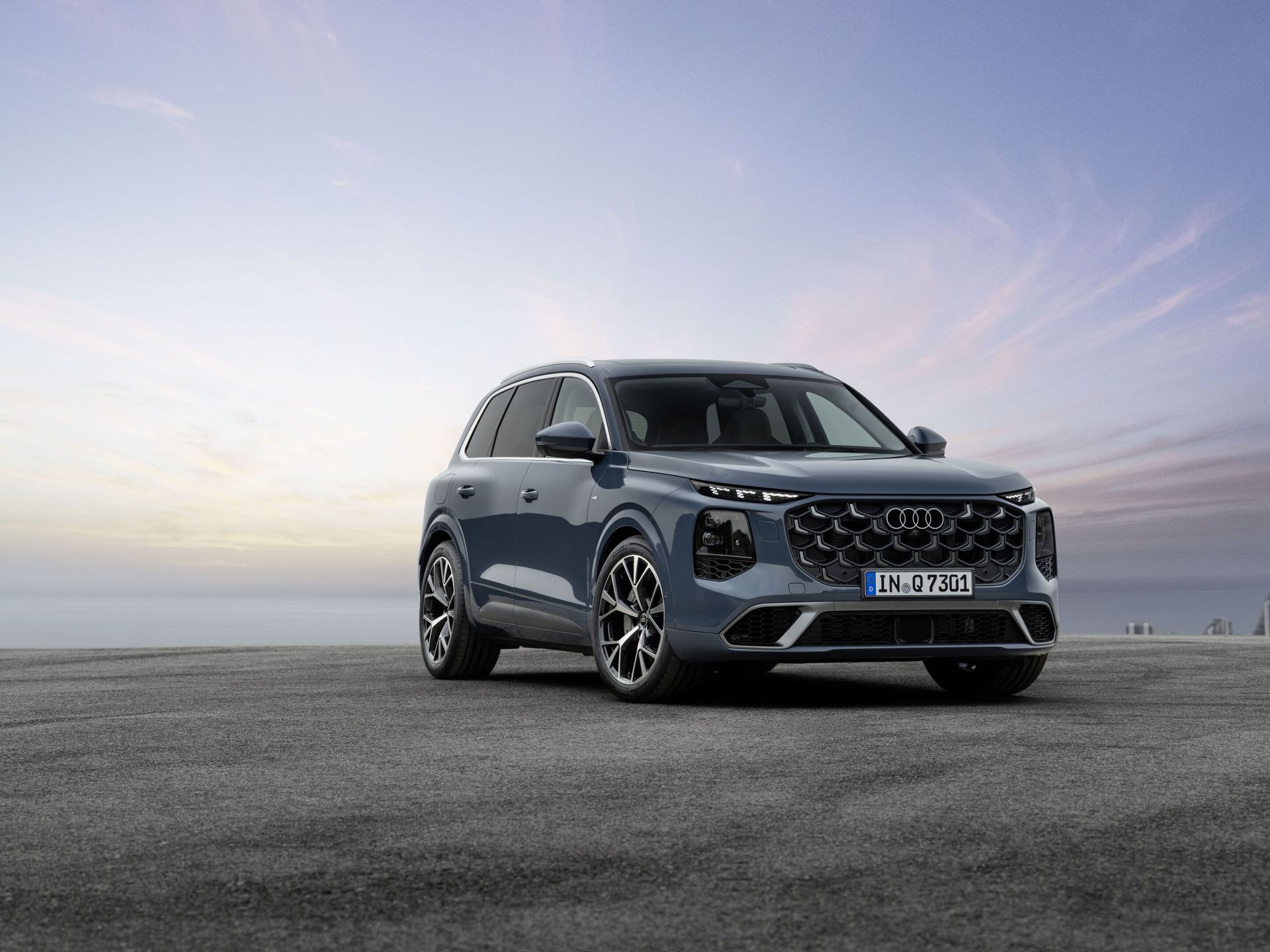Audi Q7 — przód i bok, efektowne ujęcie 3/4 na tle zachodzącego słońca nad morzem