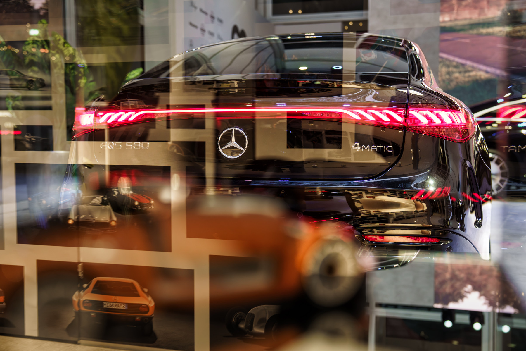 Mercedes-Benz EQS — tył widziany przez szybę z odbiciami wnętrza studia