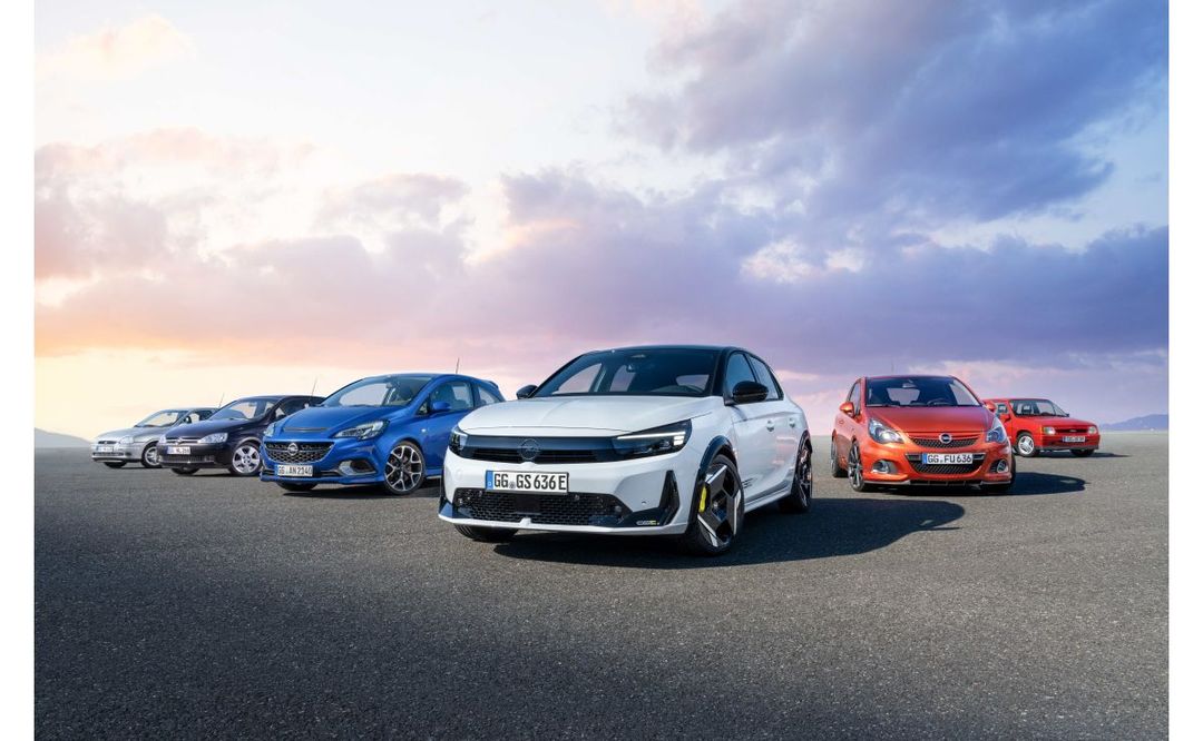 Opel Corsa GSE — przód, biały hatchback na tle rzędu poprzednich generacji modelu Corsa