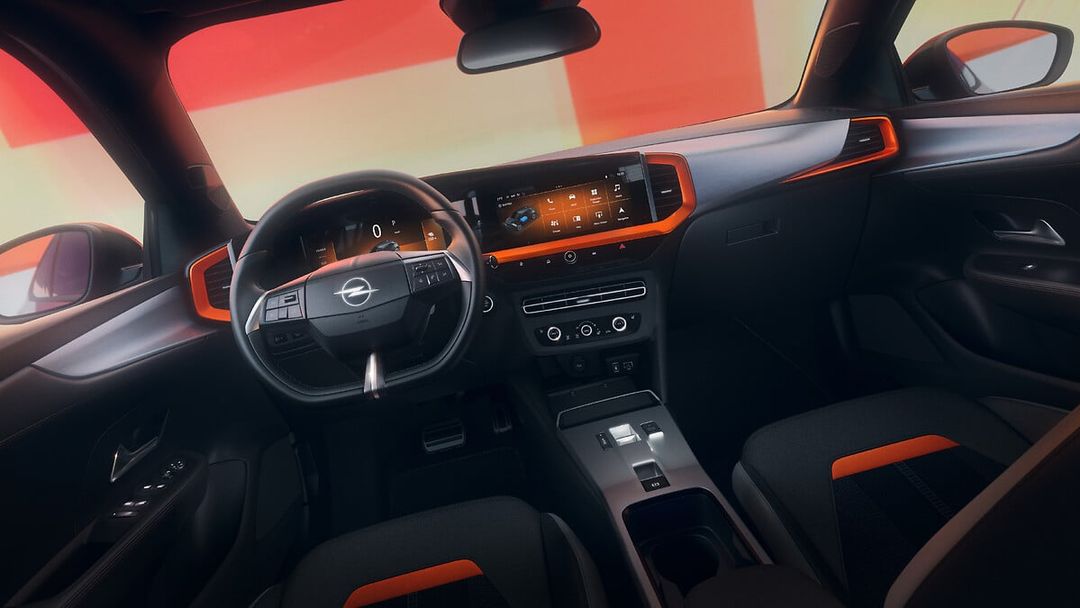 Opel Mokka YES — wnętrze, kierownica po lewej stronie, deska rozdzielcza z pomarańczowymi akcentami