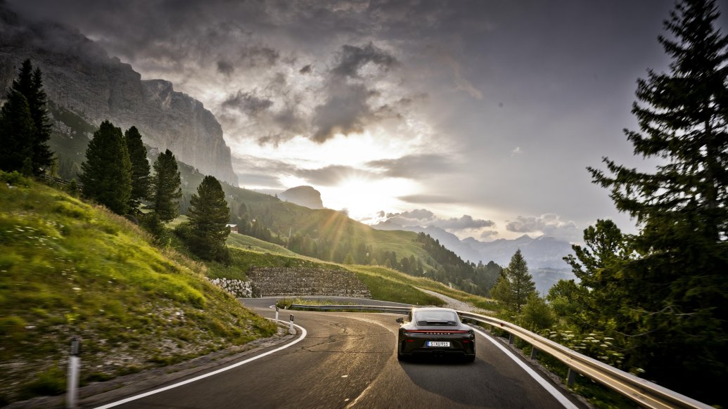 Porsche 911 GT3 Bergsport — tył, jazda górską drogą o zachodzie słońca