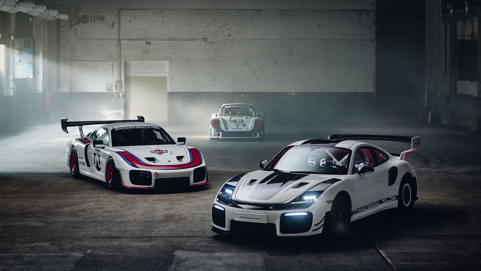 Porsche 911 GT2 RS Flachbau RS obok klasycznego Porsche 935 — ujęcie 3/4 przód w hali fabrycznej