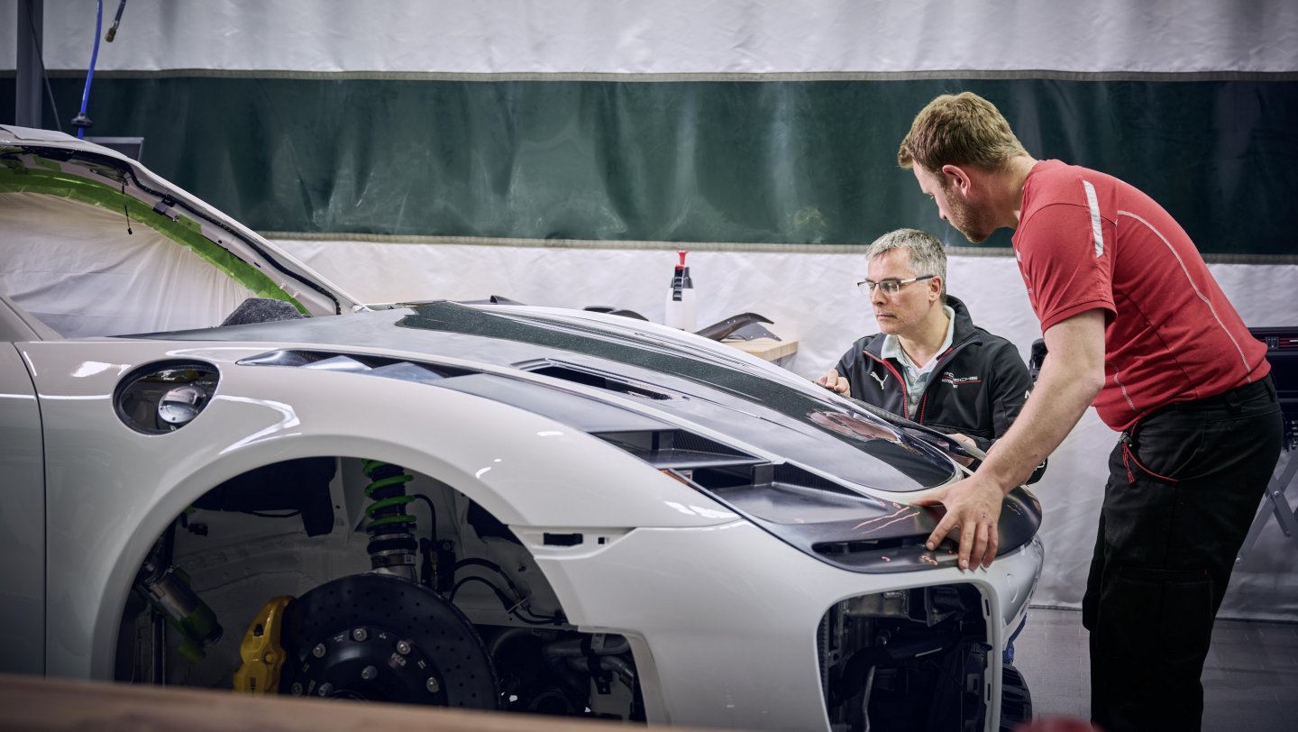 Technicy Porsche przy montażu przedniej maski modelu Flachbau RS w warsztacie