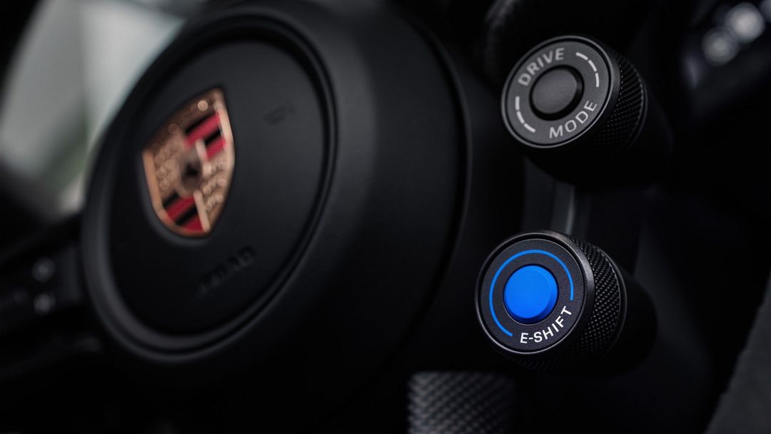 Porsche Taycan — zbliżenie na kierownicę z logo Porsche i pokrętłem E-Shift