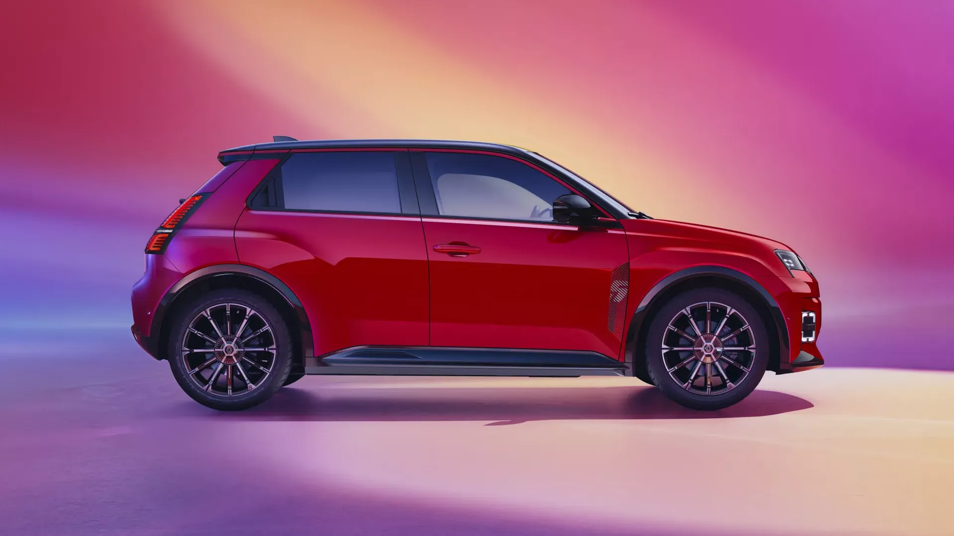 Renault 5 E-Tech — czerwony hatchback, widok z boku na kolorowym tle studyjnym