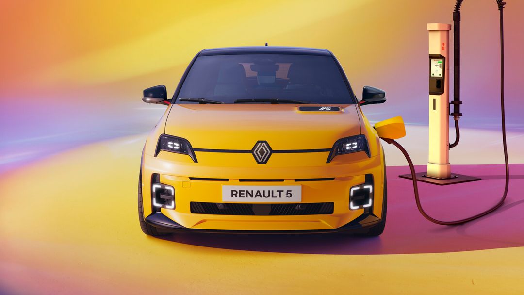 Renault 5 E-Tech — żółty hatchback od przodu, podłączony do stacji ładowania DC