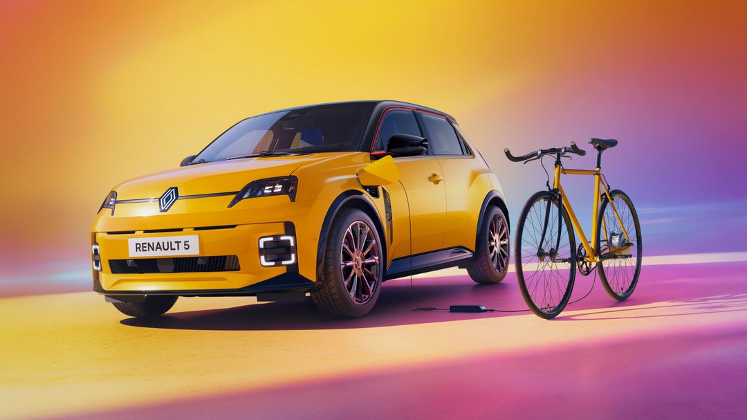 Renault 5 E-Tech — żółty hatchback od przodu obok żółtego roweru miejskiego