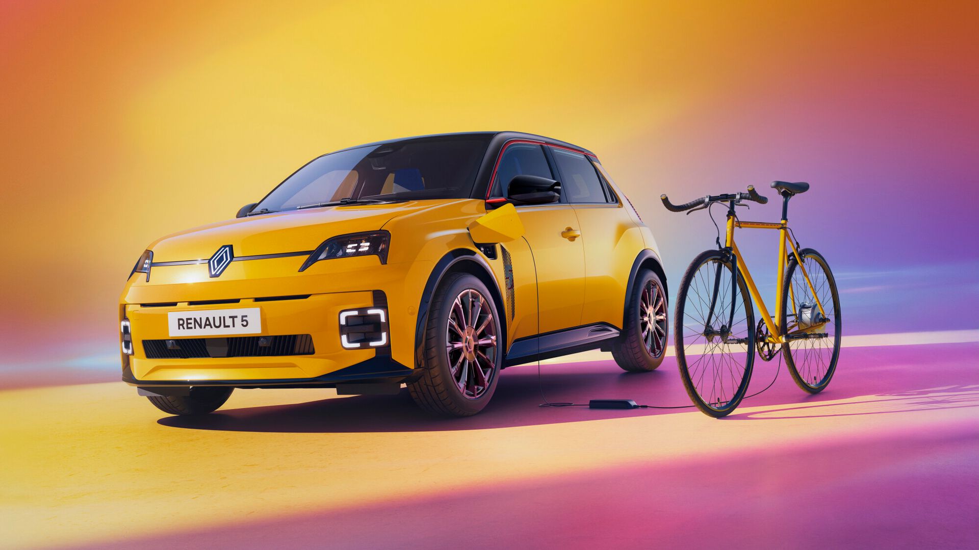 Renault 5 E-Tech — żółty hatchback od przodu obok żółtego roweru miejskiego