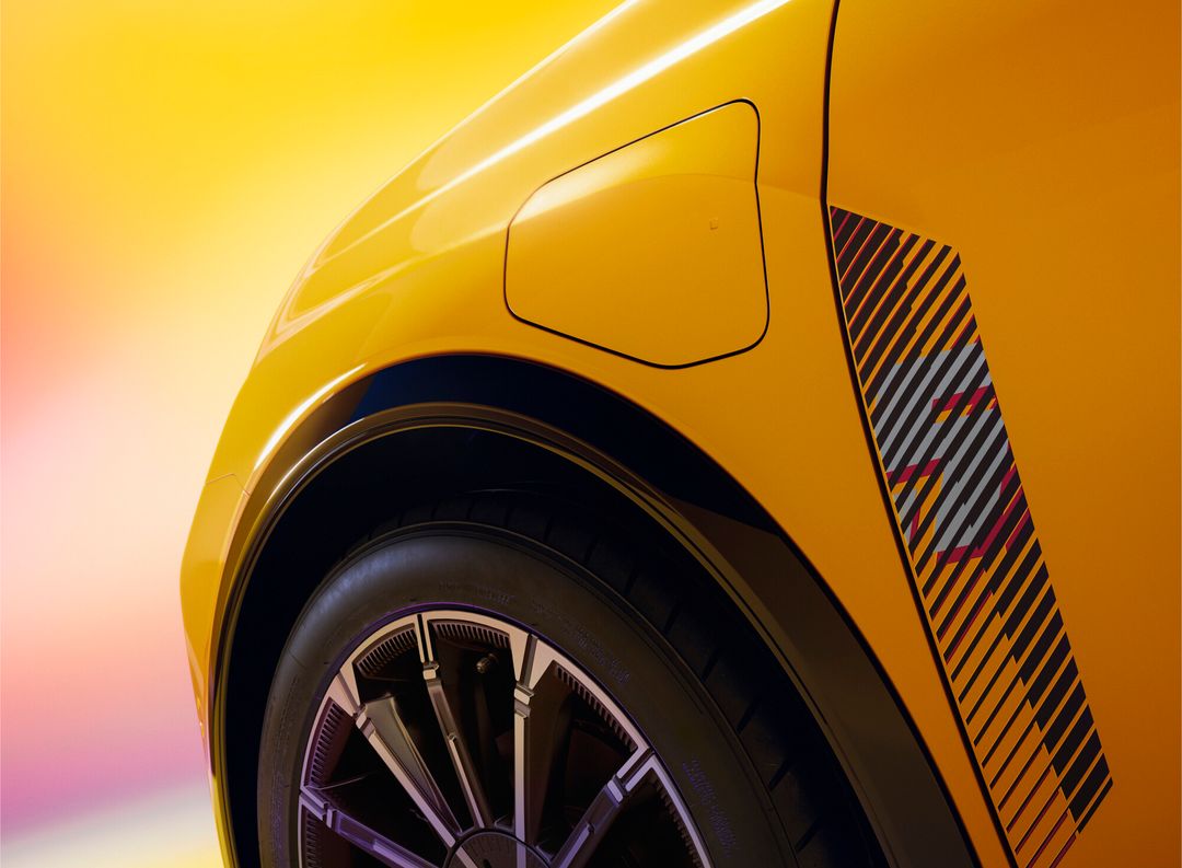 Renault 5 E-Tech — detal błotnika i klapki wlewu ładowania na żółtym nadwoziu