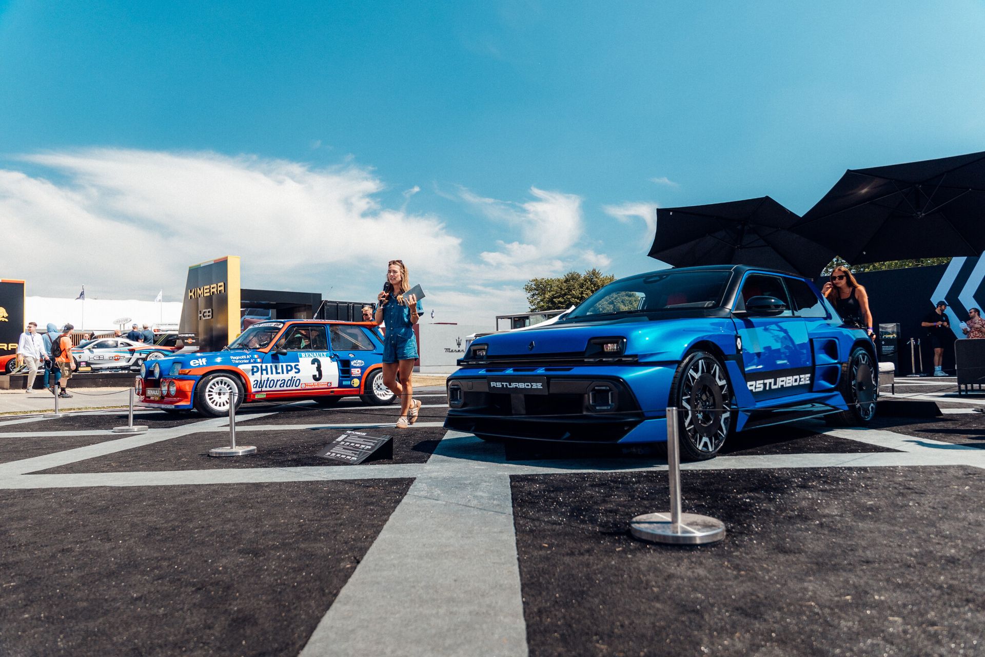 Renault 5 Turbo 3E — niebieski egzemplarz na stoisku, w tle klasyczny rajdowy Renault 5 Turbo