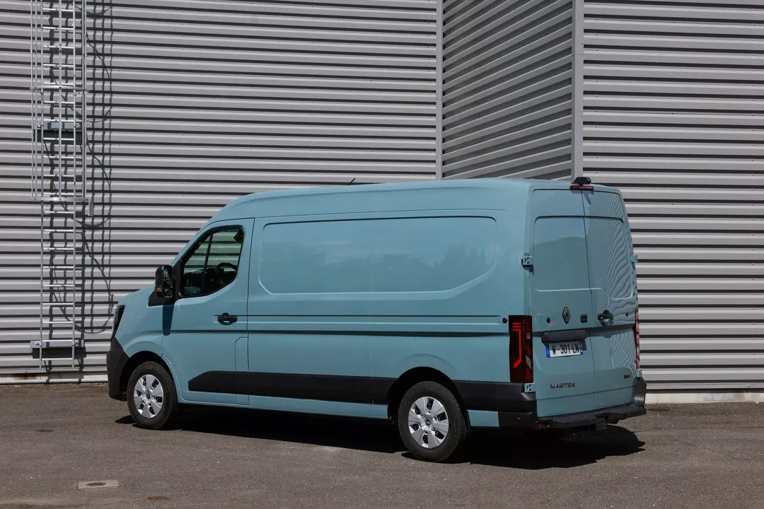Renault Master (furgon, kolor błękitny) — bok i tył, postój przy hali z blachy falistej