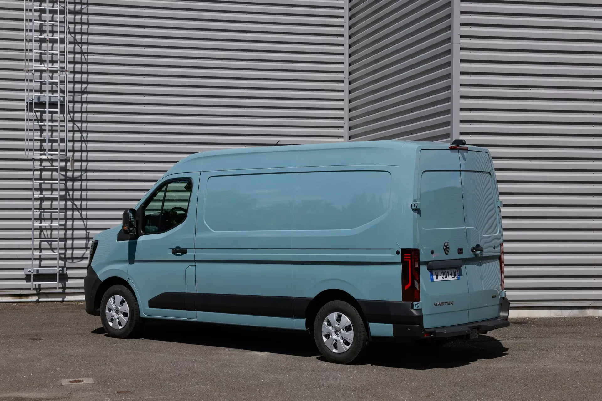 Renault Master (furgon, kolor błękitny) — bok i tył, postój przy hali z blachy falistej