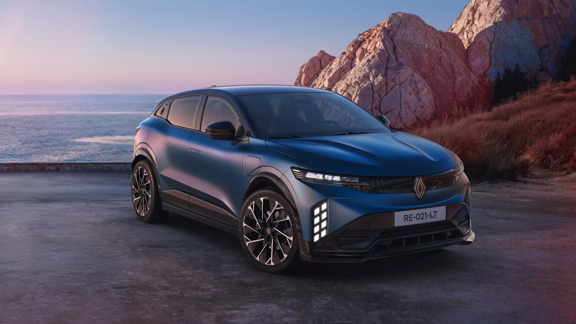 Renault Megane E-Tech Electric — przód/bok, zaparkowany na klifie nad morzem o zmierzchu