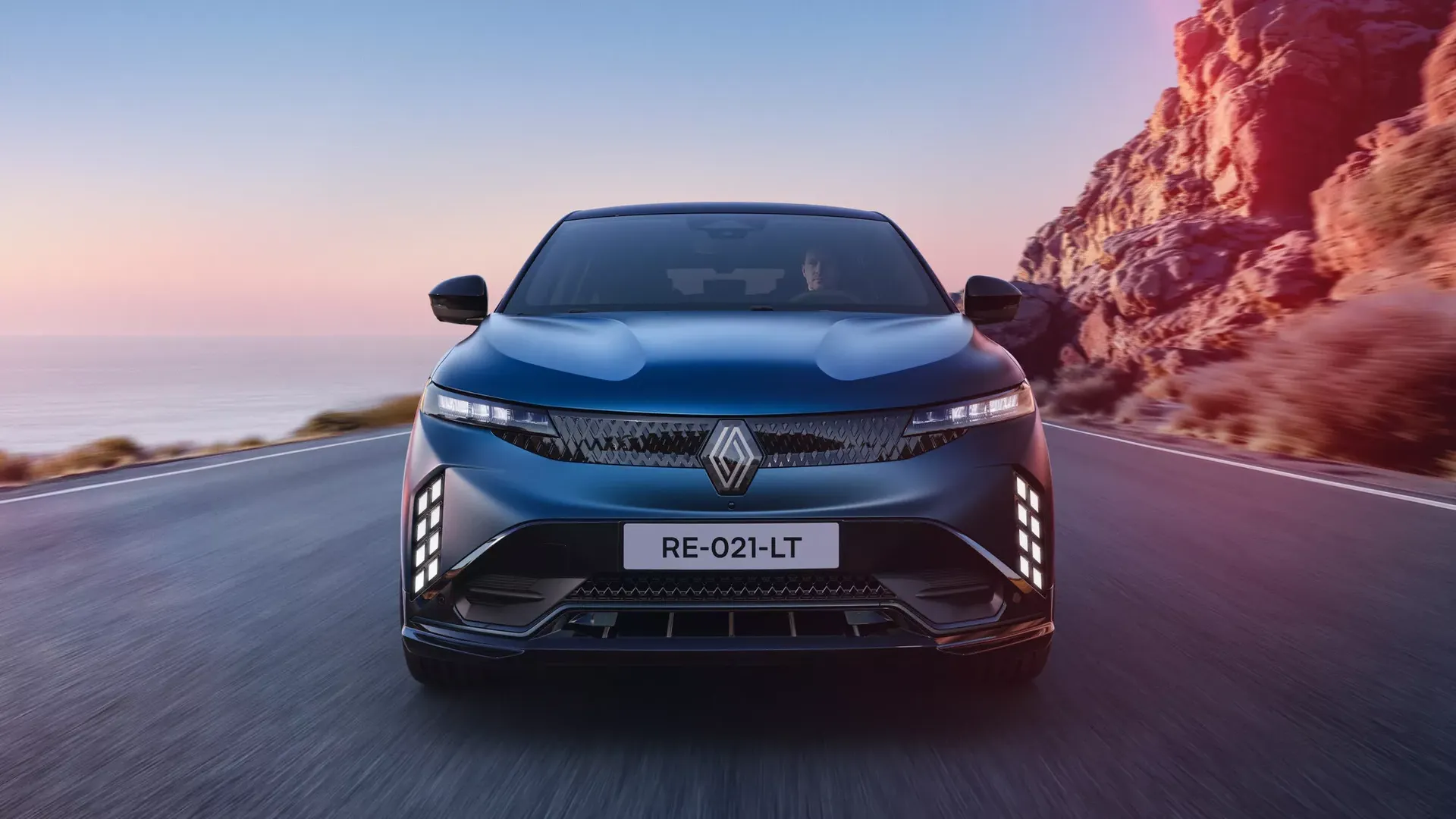 Renault Megane E-Tech Electric — przód, jazda drogą nadmorską, widoczny kierowca za kierownicą