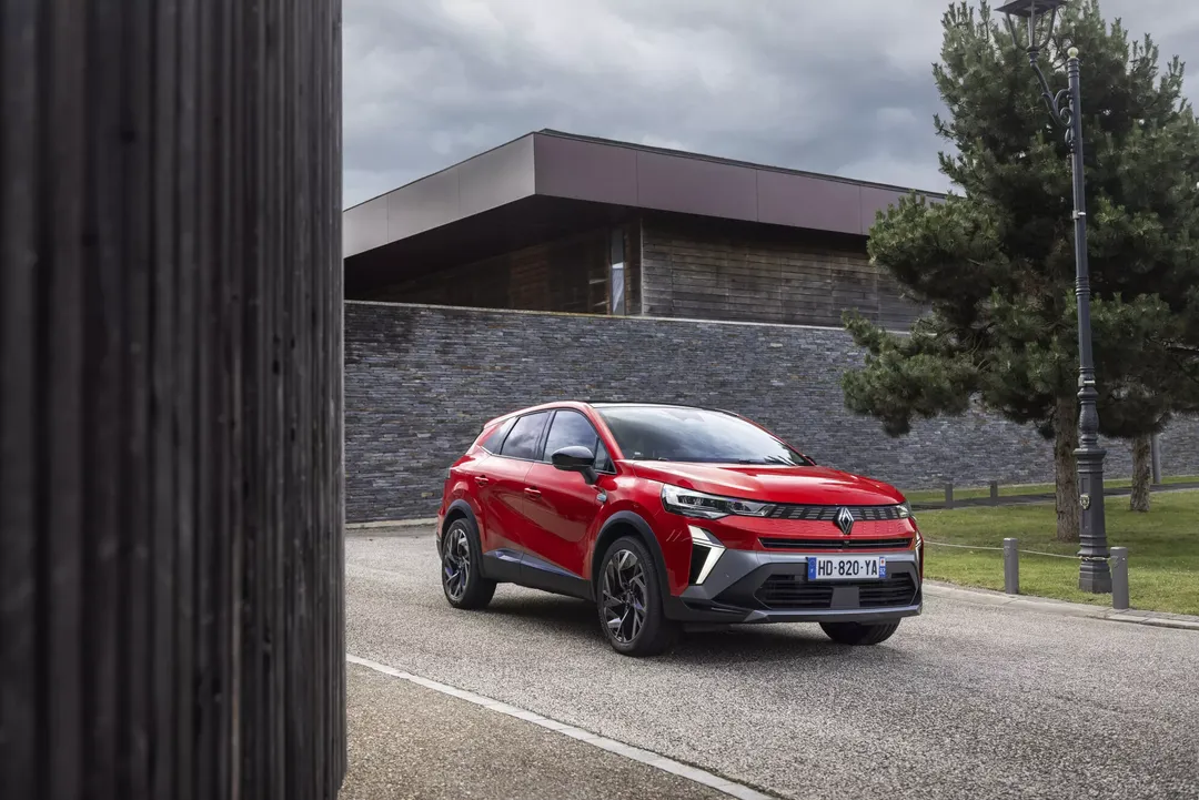 Renault Symbioz — przód i bok, czerwony SUV zaparkowany przed nowoczesnym domem