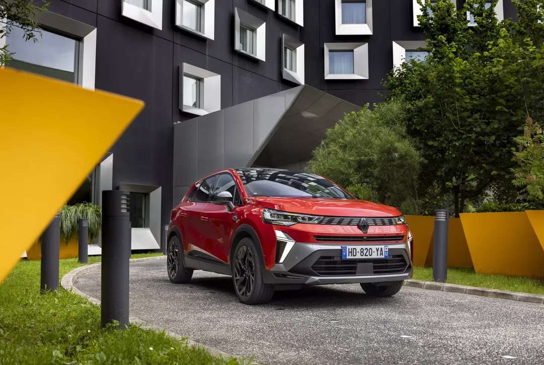 Renault Symbioz — zbliżenie przodu, czerwony SUV przed wejściem do budynku