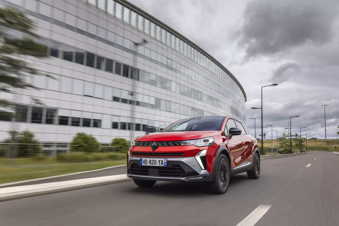 Renault Symbioz — dynamiczna jazda, czerwony SUV na tle nowoczesnego budynku biurowego
