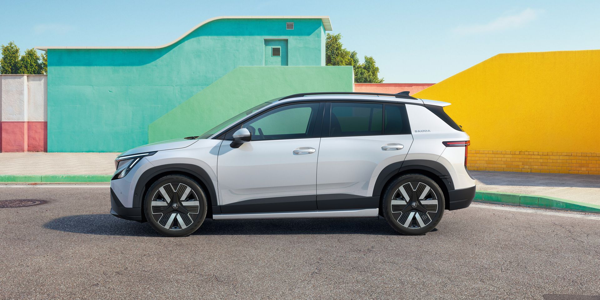 Škoda Epiq — profil boczny, białe nadwozie dwukolorowe, kolorowe tło architektoniczne