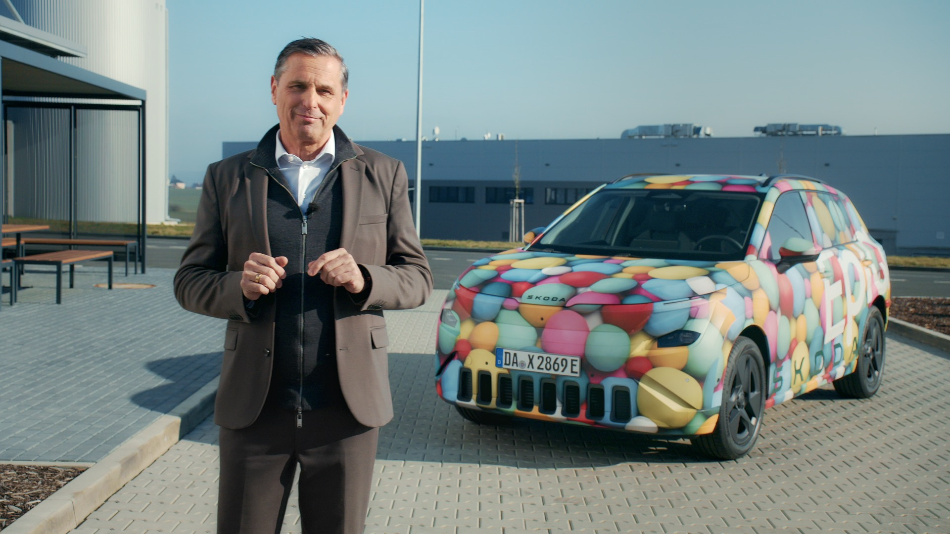 Škoda Epiq — prototyp w kamuflażu kolorowym, dyrektor Škoda przed budynkiem fabryki