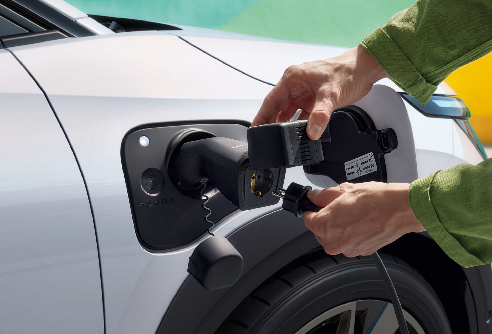 Škoda Epiq — dłonie podłączające ładowarkę do gniazda w błotniku