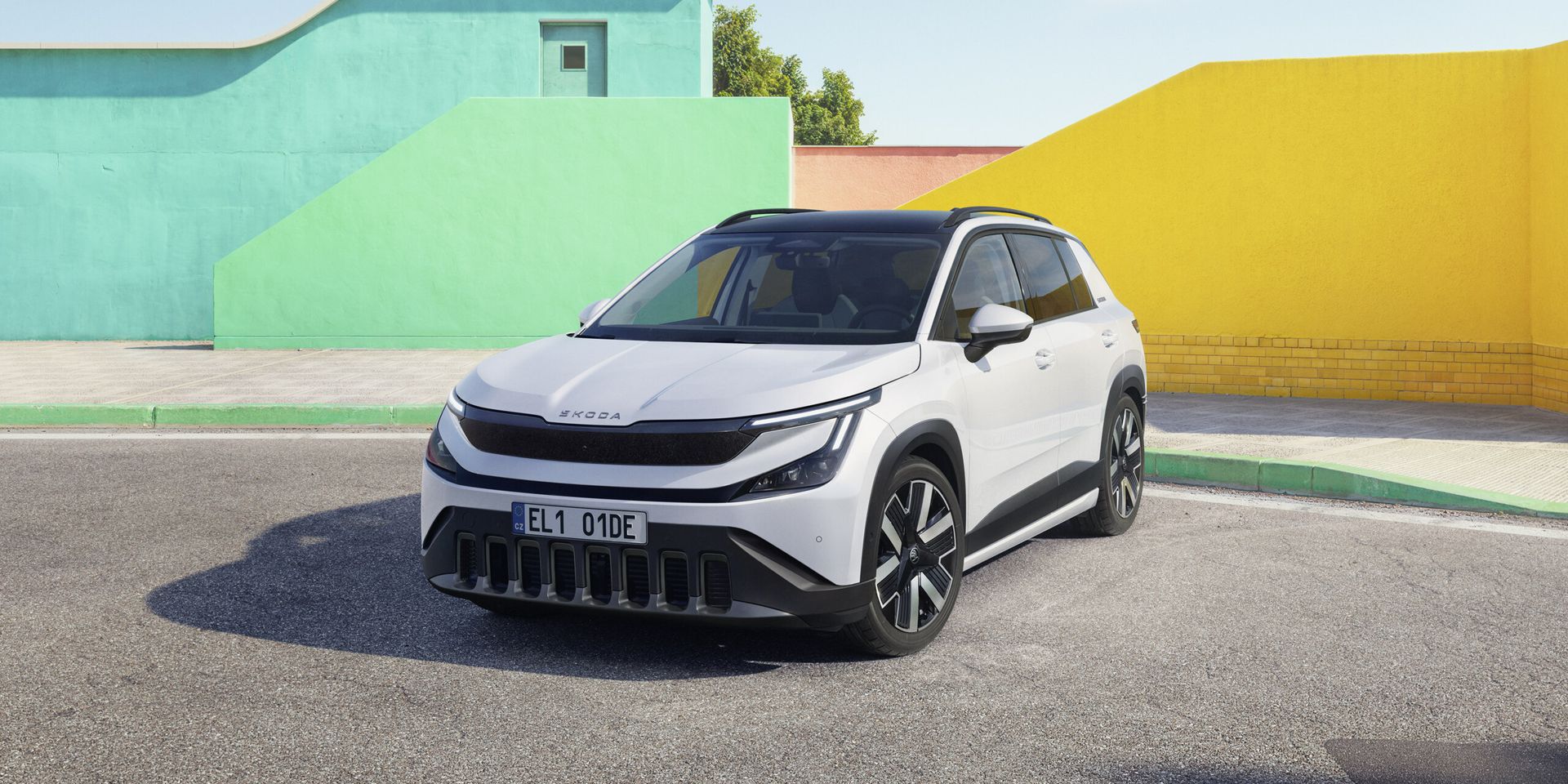 Škoda Epiq — przód i bok, biały SUV na tle kolorowych murów