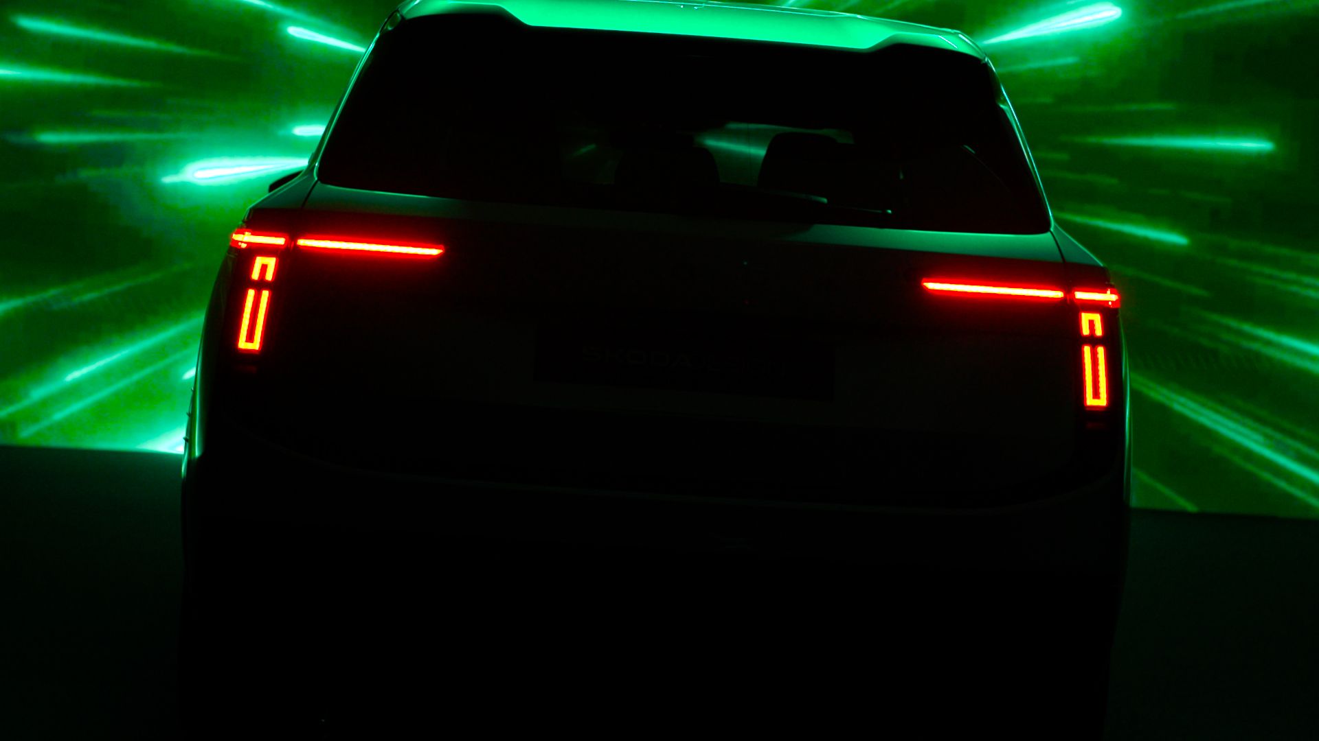 Škoda Peaq — teaser tylnych lamp LED, ciemne ujęcie studyjne z dramatycznym zielonym tłem świetlnym