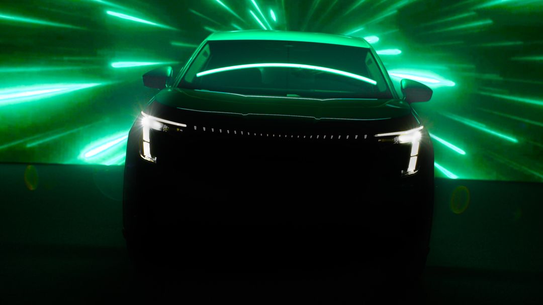 Škoda Peaq — teaser przednich świateł LED i atrapy, ciemne ujęcie studyjne z zielonym tłem świetlnym