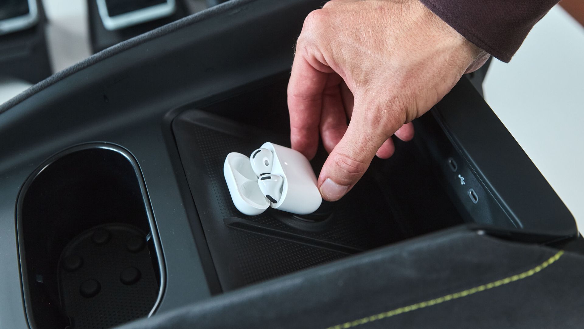 Škoda — schowek na bezprzewodowe słuchawki w konsoli środkowej, dłoń wkładająca słuchawki