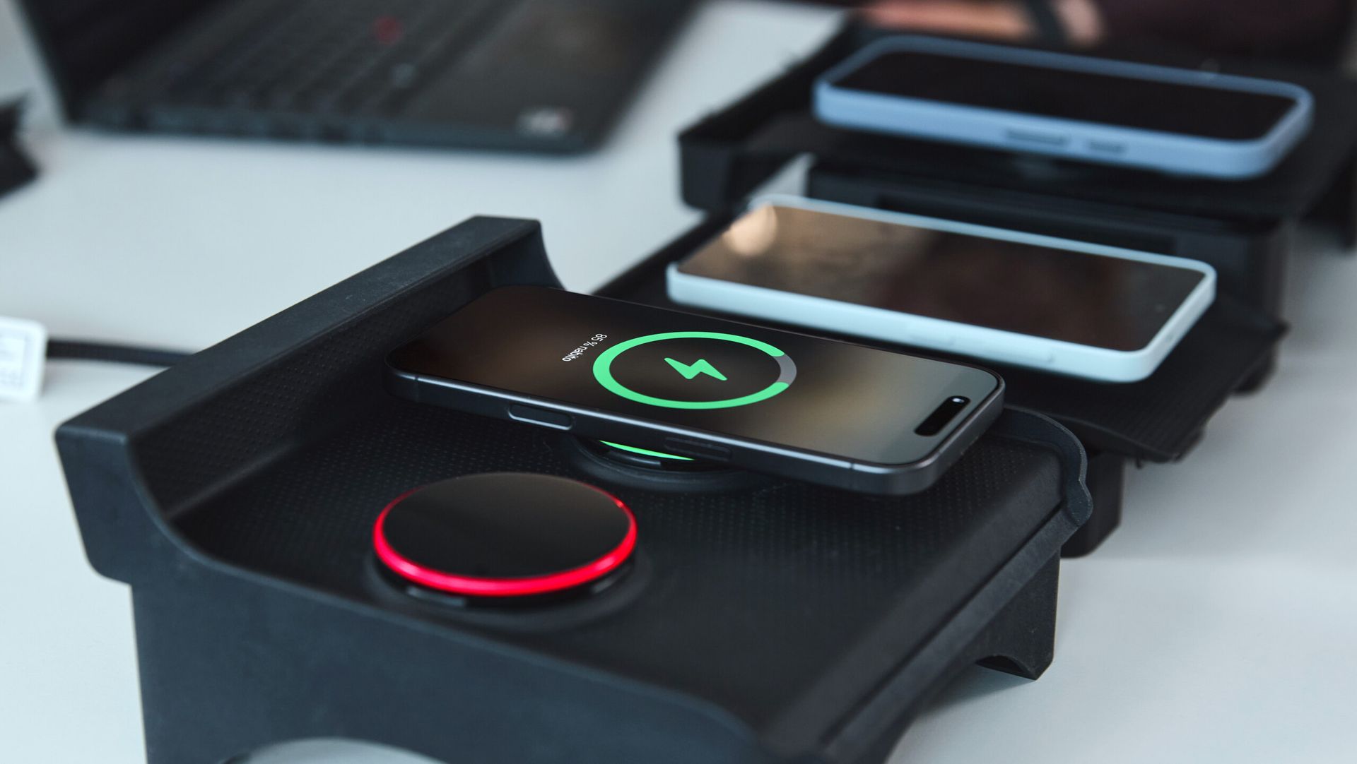 Prototyp ładowarki indukcyjnej Qi2 z telefonami testowymi na biurku inżynierskim (powtórzone ujęcie)