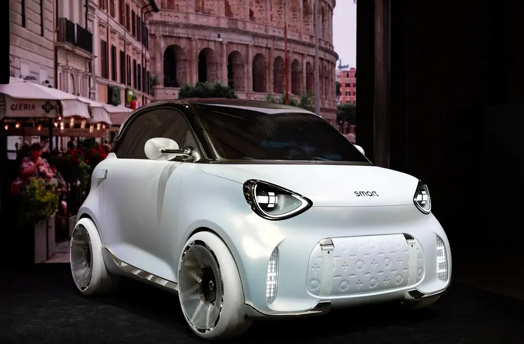 smart — przód i bok, biały concept car na stoisku targowym, w tle Koloseum
